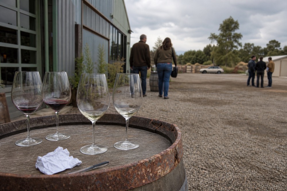 A small group of wine glasses on a barrel-top table in a winery
