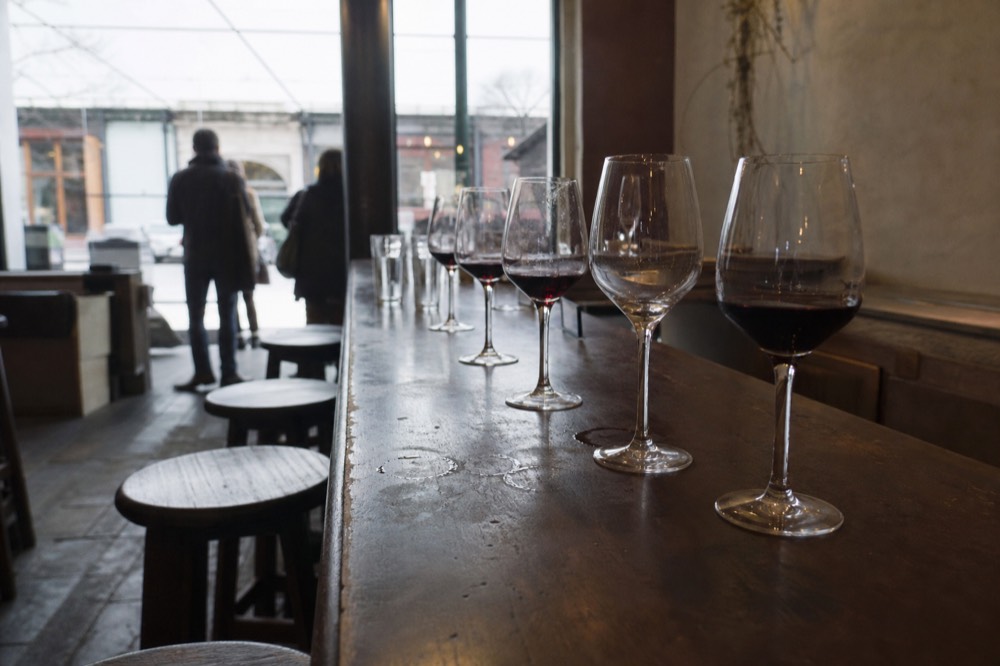 Tasting room interior with glasses of red wine lined along a wooden bar