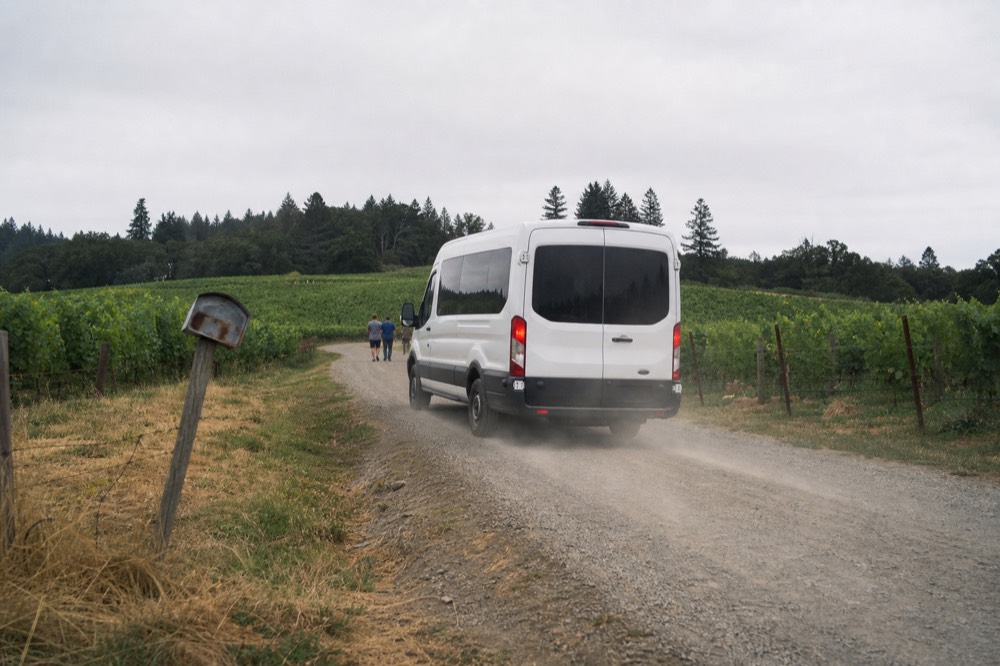 A shuttle van on a country road between vineyards near Carlton
